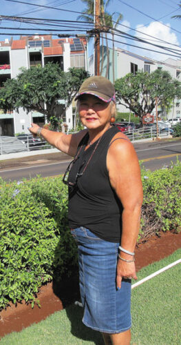 LAHAINA NEWS Deb Uli'i stands on her front lawn and points to Hale Mahina Beach Resort directly across the street. Since 1977, the condo complex has been required to provide shoreline access for local residents, but has yet to do so. The neighborhood has been shut out of the beach for more than 40 years. PHOTO BY SUSAN HALAS.